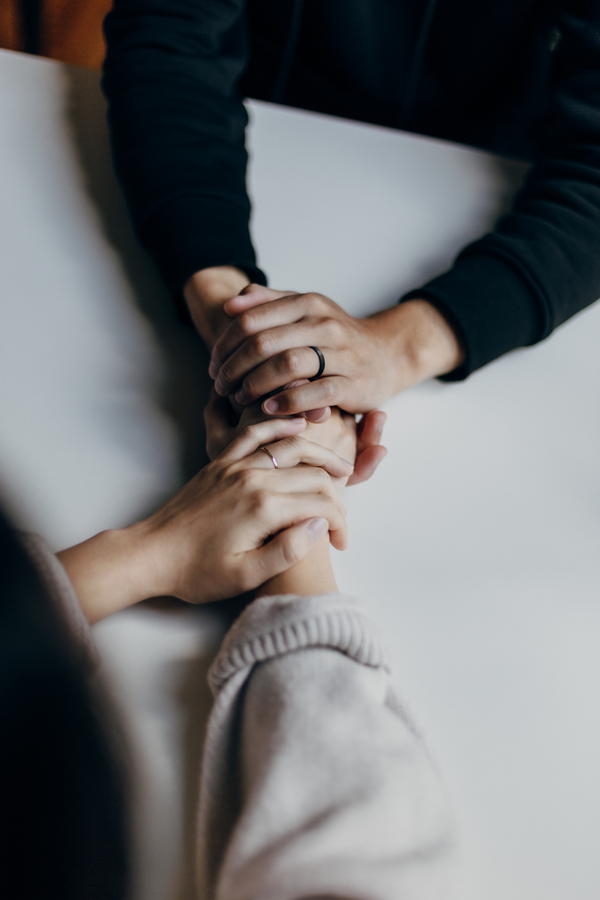 Mãos de duas pessoas sobrepostas em gesto de apoio e acolhimento